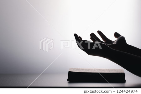 Hands in prayer on holy bible in church concept for faith, spirituality and religion. Unrecognizable woman holding a bible in her hands and praying. Hands clasped in prayer over holy bible. Hands in prayer on holy bible in church concept for faith, spirituality and religion. Unrecognizable woman holding a bible in her hands and praying. Hands clasped in prayer over holy bible. 124424974