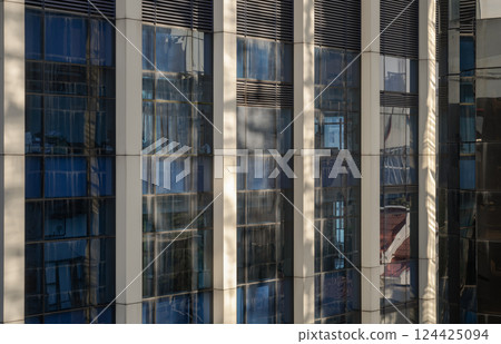 Perspective view of modern building facade with blue sky and clouds reflection in windows. Perspective view of modern building facade with blue sky and clouds reflection in windows. 124425094