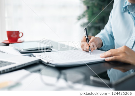 Close up businesswoman signing documents. Hand of woman write business document charts at office desk. Woman signing document, focus on female hand holding pen, putting signature at official paper. Close up businesswoman signing documents. Hand of woman write business document charts at office desk. Woman signing document, focus on female hand holding pen, putting signature at official paper. 124425266