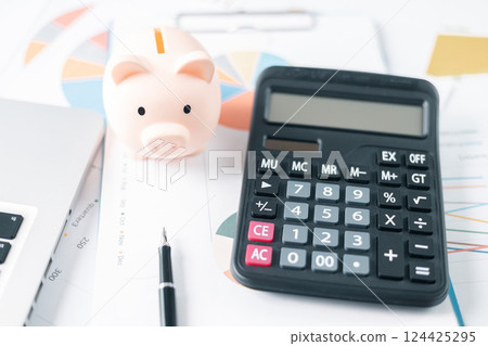 Piggy bank with business stuff, business and finance concept. calculators on financial statements, business chart showing financial success at the stock market 124425295