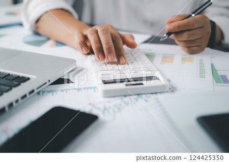 Business financing accounting banking concept. Businesswoman hand doing finances and calculate on desk about cost at home office. Woman working on desk with using calculator, finance accounting. 124425350