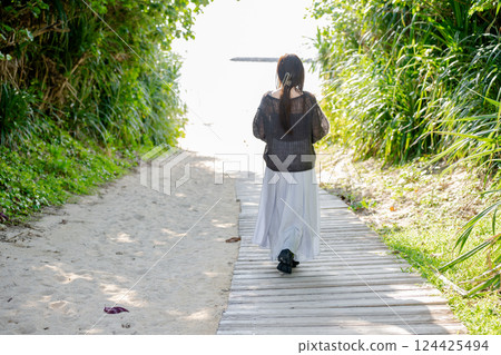 Woman walking towards the beach 124425494