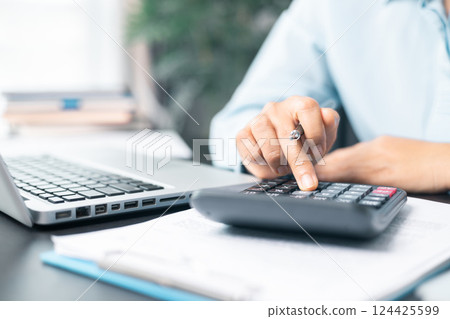 Business woman working on documents looking concentrated with briefcase on table. Businesswoman is deeply reviewing a financial report for a return on investment or investment risk analysis. 124425599