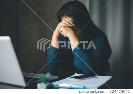 Stressed business woman. Tired business woman sleepy and bored from sitting at a desk for a long time and has office syndrome. Bored woman in office working with laptop and staring at computer screen 124425642