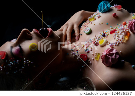 Woman adorned with colorful body art and sweets in a creative display Woman adorned with colorful body art and sweets in a creative display 124426127