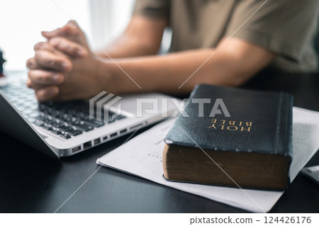 Christian online religion technology concept. Hands praying of christian with digital computer laptop, Online live church for sunday service. Asian woman praying in darkness with computer laptop. 124426176