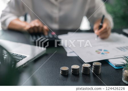 Human hand stacking coins over office background. Concept of investment management and portfolio diversification. Business diagram on financial report with coins. 124426226