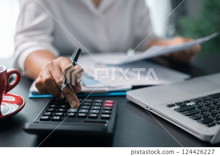 Businesswoman working on desk office with using a calculator to calculate the numbers, finance accounting concept. Woman accountant use calculator and computer. tax, accounting, statistics 124426227