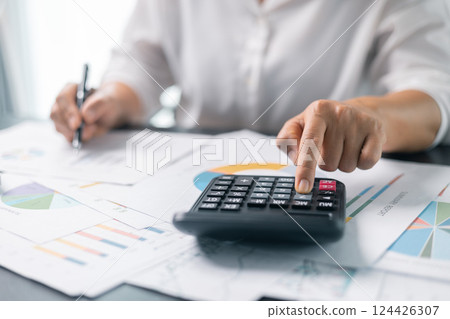 Businesswoman working on desk office with using a calculator to calculate the numbers, finance accounting concept. Woman accountant use calculator and computer. tax, accounting, statistics Businesswoman working on desk office with using a calculator to calculate the numbers, finance accounting concept. Woman accountant use calculator and computer. tax, accounting, statistics 124426307