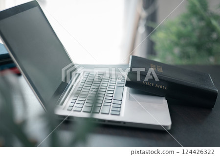 Cross on bible and laptop in online study bible concept. Holy Bible concept for modern religious education, podcast or help with hearing for blind studying 124426322