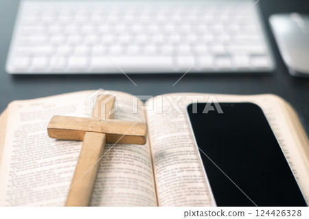 Cross on bible and laptop in online study bible concept. Holy Bible concept for modern religious education, podcast or help with hearing for blind studying Cross on bible and laptop in online study bible concept. Holy Bible concept for modern religious education, podcast or help with hearing for blind studying 124426328