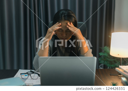 Depression at work. Asian Businesswoman sitting and working hard at with front of computer and lots of documents on table in workplace at late with serious action, Work hard and too late concept 124426331