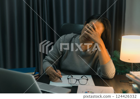 Depression at work. Asian Businesswoman sitting and working hard at with front of computer and lots of documents on table in workplace at late with serious action, Work hard and too late concept Depression at work. Asian Businesswoman sitting and working hard at with front of computer and lots of documents on table in workplace at late with serious action, Work hard and too late concept 124426332