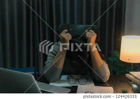 Depression at work. Asian Businesswoman sitting and working hard at with front of computer and lots of documents on table in workplace at late with serious action, Work hard and too late concept 124426333