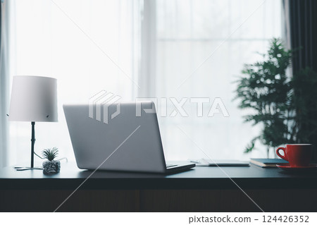 Office workplace with laptop and smart phone on wood table. Workspace, desktop computer, office supplies, houseplant and books at office. desk work concept. laptop Comfortable work table in office. 124426352