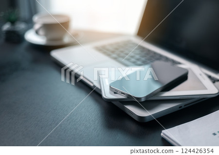 Office workplace with laptop and smart phone on wood table. Workspace, desktop computer, office supplies, houseplant and books at office. desk work concept. laptop Comfortable work table in office. 124426354
