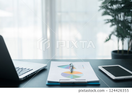 Office workplace with laptop and smart phone on wood table. Workspace, desktop computer, office supplies, houseplant and books at office. desk work concept. laptop Comfortable work table in office. 124426355