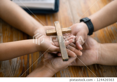 Group of Christian believers clasped hands in prayer, In the church, expressing their faith through worship and reverence for God, symbolized by the cross. Group christian pray concept. 124426563