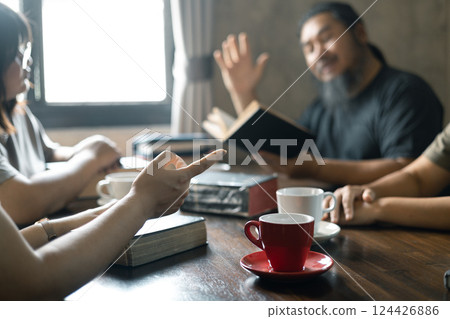 Christian woman held her Bible close as she joined hands with the group in prayer, their faith uniting them together in a religious bond during their prayer session. Group christian pray concept. 124426886