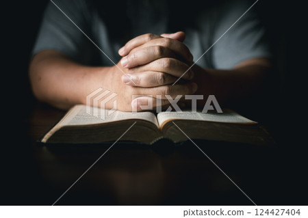 Man with holy bible in his hand, ready to pray, seek guidance from God through religious prayer. Person man, turned to God in prayer, demonstrating their religious faith and devotion through worship. 124427404