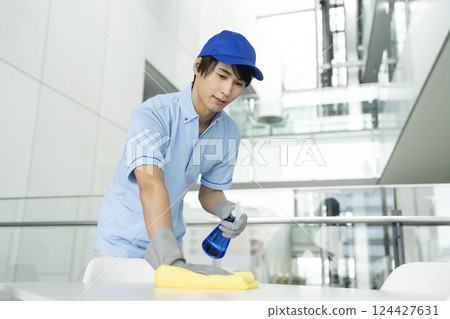 A young male cleaning staff member wiping the floor 124427631