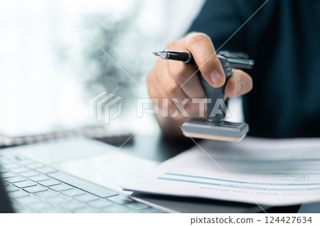 Businesswoman confidently placed her stamp of approval on legal document, finalizing the contract and solidifying the agreement in office with her authority. document, approve, business, stamp. 124427634