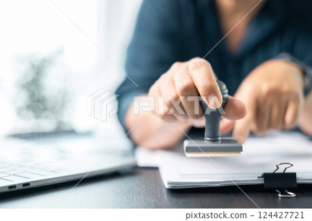 Banking officer stamped the document to approve the loan, finalizing the contract and solidifying the finance agreement, fundamental concept in business transactions. approve, loan, stamp, business. 124427721