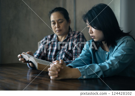 Hands clasped in prayer, Christians express their faith in God and worship Jesus Christ in the church, finding guidance and solace in the teachings of the Bible and their religious beliefs. 124428102