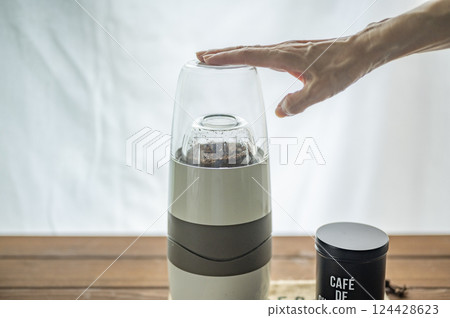 用電動研磨機研磨烘焙後的咖啡豆 用電動研磨機研磨烘焙後的咖啡豆 124428623