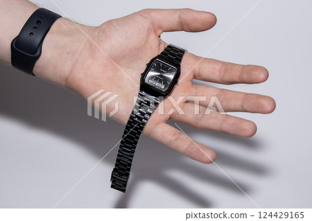 Black watch with hands and electronic dial on a human palm. Black watch with hands and electronic dial on a human palm. 124429165
