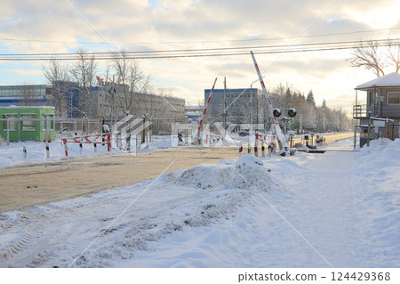 A snowy winter scene at a railway crossing with beautiful buildings in a serene setting 124429368