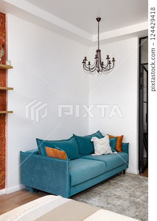 A Stylish Teal Sofa Nested in a Modern Living Space Enhanced by an Elegant Chandelier 124429418