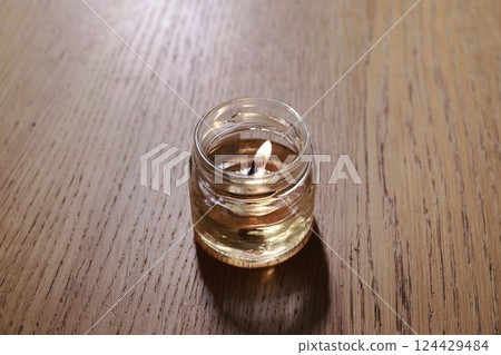 A soothing candle elegantly placed in a glass jar resting on a beautiful wooden surface 124429484