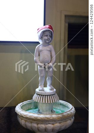 Charming and Elegant Fountain Boy Statue Adorned with a Festive Holiday Hat for Joyful Decor 124429566