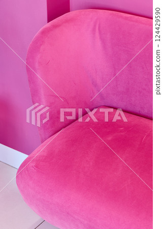 A Vibrant Pink Upholstered Chair Positioned Beautifully Against a Bold Pink Wall Background A Vibrant Pink Upholstered Chair Positioned Beautifully Against a Bold Pink Wall Background 124429590
