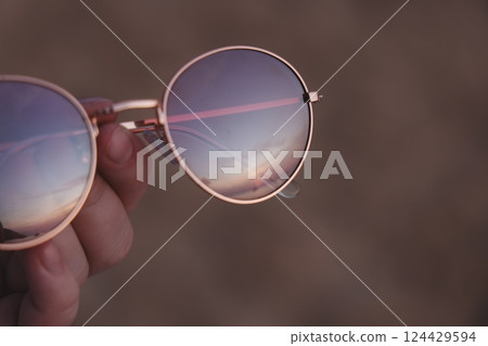 The Stunning Reflection of a Truly Beautiful Sunset Glimmering in Trendy and Stylish Sunglasses The Stunning Reflection of a Truly Beautiful Sunset Glimmering in Trendy and Stylish Sunglasses 124429594
