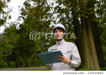A woman in work clothes performing maintenance 124429663