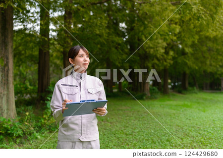A woman in work clothes performing maintenance A woman in work clothes performing maintenance 124429680