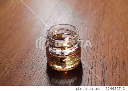 A beautiful glass jar filled with a vibrant liquid, elegantly resting on a wooden surface A beautiful glass jar filled with a vibrant liquid, elegantly resting on a wooden surface 124429742