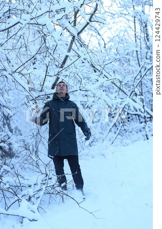 A person enjoying a Winter Wonderland experience, surrounded by beautiful snowy trees A person enjoying a Winter Wonderland experience, surrounded by beautiful snowy trees 124429743