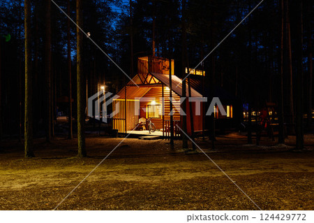 A Cozy Cabin That Is Beautifully Illuminated by Night in a Serene Forest Setting A Cozy Cabin That Is Beautifully Illuminated by Night in a Serene Forest Setting 124429772