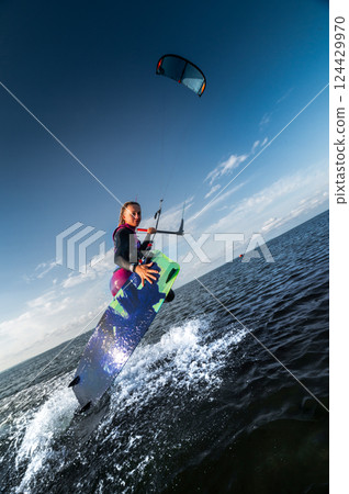 woman at sea rides a kiteboard surfboard using a kite wing. Extreme sport, fast travel across the sea on a board 124429970