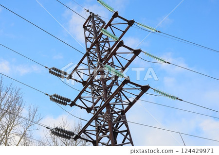A Tall High Voltage Power Transmission Tower Stands Majestically Against A Clear Blue Sky 124429971