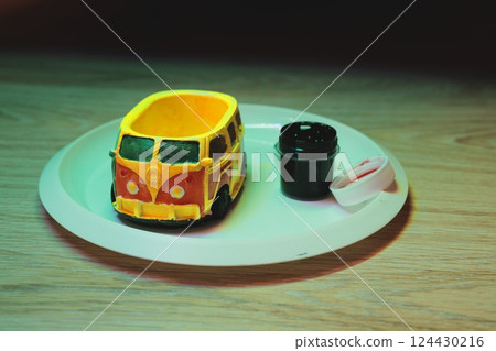 A Colorful Toy Van Artistically Arranged on a Plate Surrounded by Fun Accessories 124430216