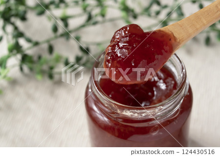 Lifting a spoonful of strawberry jam from a jar 124430516