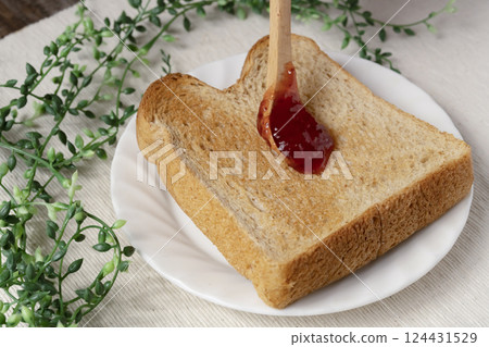 將瓶裝草莓醬塗在烤麵包上 將瓶裝草莓醬塗在烤麵包上 124431529