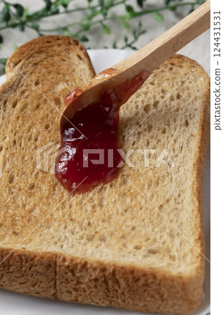 將瓶裝草莓醬塗在烤麵包上 將瓶裝草莓醬塗在烤麵包上 124431531