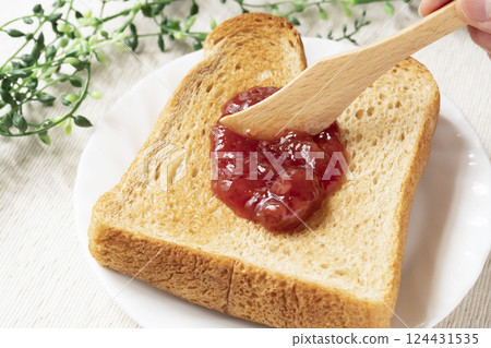 Spread bottled strawberry jam on toasted bread Spread bottled strawberry jam on toasted bread 124431535