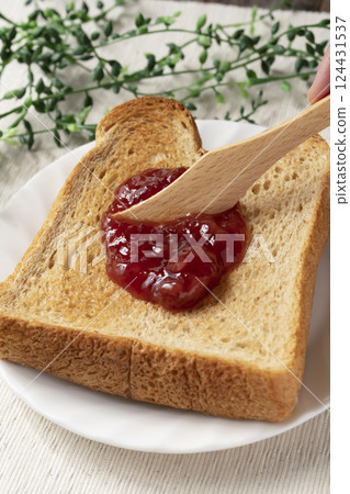 Spread bottled strawberry jam on toasted bread Spread bottled strawberry jam on toasted bread 124431537