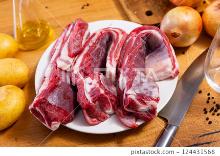 Raw beef ribs on board, potato tubers and whole onions 124431568